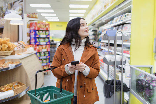 Woman with smart phone shopping in supermarket