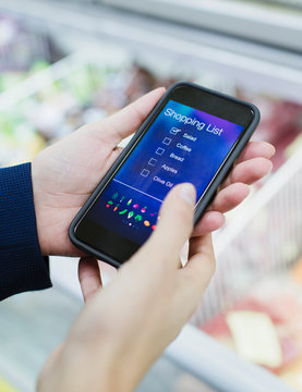 Close up woman using digital shopping list on smart phone supermarket