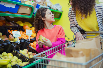 Mother and daughter shopping for produce in supermarket