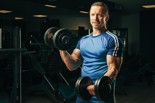 Senior man in his fifties lifting weights in a gym