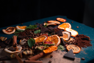 dark decorated table with coffee beans, dry oranges,dry lemons,dry Sabras fruit,dry kiwi,dark chacolate,cinnamon sticks..place for the text.