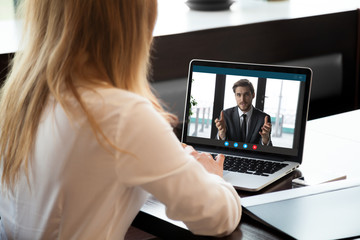 Back view of female employee talk on video call with male colleague or business partner, woman...