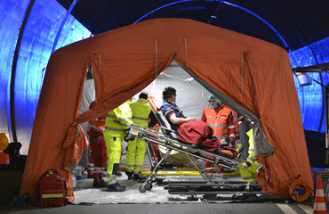 Alert Covid-19. Man on stretcher is visited inside a temporary hospital field tent for the first AID for patient with Corona Virus. Zone for inspection in public place for people infected people.  © fabrus