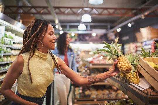 Woman shopping for pineapple in supermarket produce section
