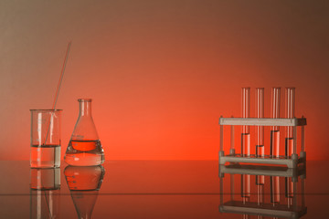Fototapeta na wymiar conceptual background with chemical flasks. red backdrop with lab glassware with copy space. conceptual background of chemistry science in laboratory