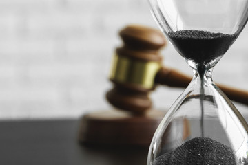 Court concept. Hourglass and judge gavel on table close up