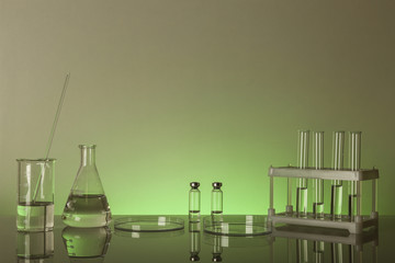 conceptual background with chemical flasks. green backdrop with lab glassware with copy space. conceptual background of chemistry science in laboratory