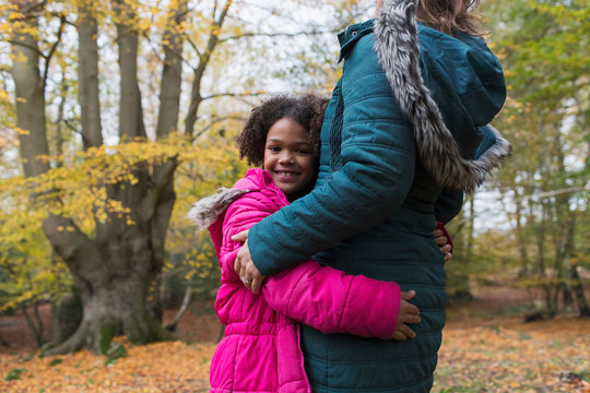 Portrait of happy girl hugging mother in autumn woods