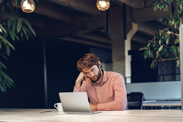 Puzzled thoughtful businessman sitting at his working table in an office. Business concept