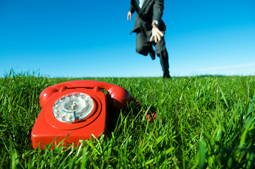 Unrecognizable businessman racing to answer an old-fashioned red rotary dial telephone ringing...