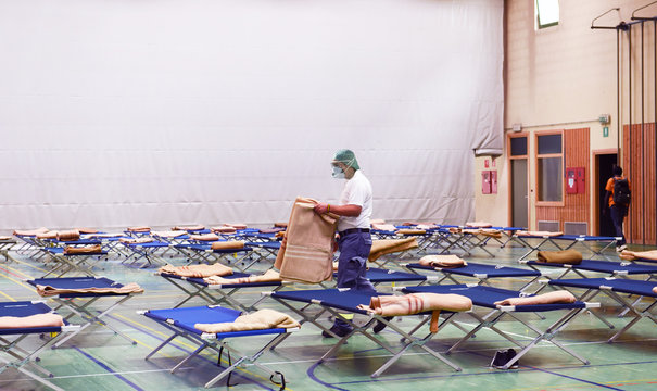 Empty Hospital Field Tent For The First AID, A Mobile Medical Unit Of Red Cross For Patient With Corona Virus. Interior Camp Room With Folding Camp Bed. Medical Staff At Work With Protective Mask.