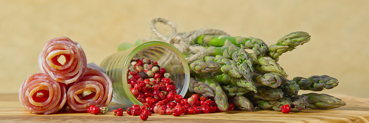 Fresh Young Asparagus with raw bacon ready for cooking. Asparagus and bacon on wood board with red pepper peas. panoramic view.