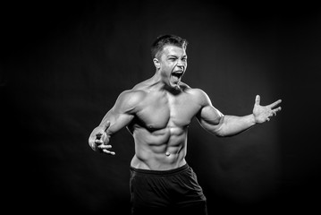 Obraz na płótnie Canvas Sexy young athlete posing on a black background in the Studio. Fitness, bodybuilding, black and white