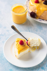 Slice of angel food cake with lemon curd and frozen berries (raspberry and blackberry), blue concrete background. 