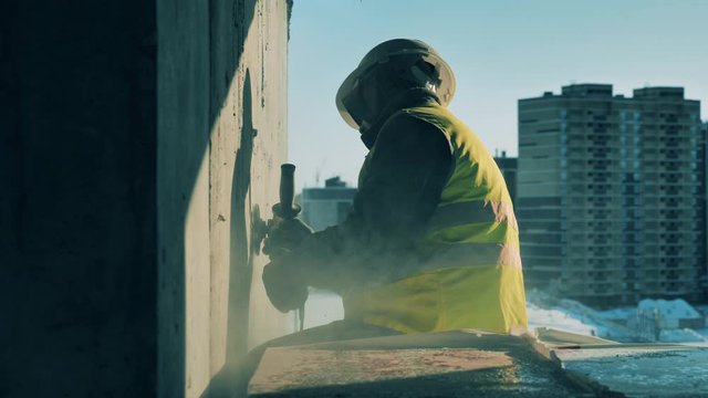 A man uses sanding machine while working on a building site.