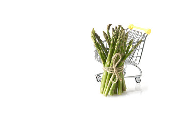 Fresh green asparagus in shopping cart isolated on white background