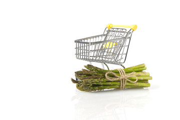Fresh green asparagus in shopping cart isolated on white background