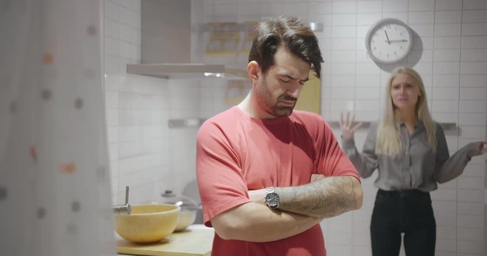Family problems. Upset wife scolding sad husband at the kitchen