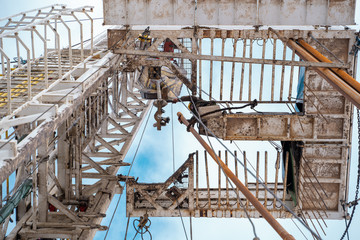 Work driller in red uniform, in helmet and goggles. He uses a hydraulic wrench to screw drill pipes...