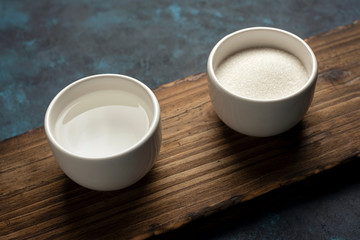 azucar y agua en cuancos blancos sobre madera ingredientes 