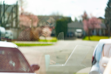 Woman working on computer inside shot through window