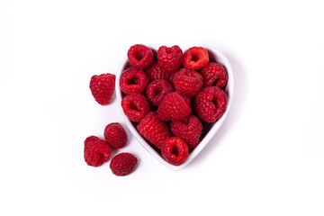 Fresh raspberries in a heart-shaped bowl isolated on a white background.