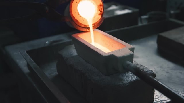 Hot and liquid precious metal is poured in a mold on a jewelry production