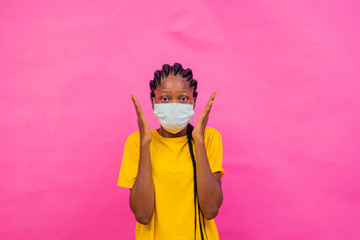 a young pretty african girl trying not to touch her face after wearing a medical face mask. 