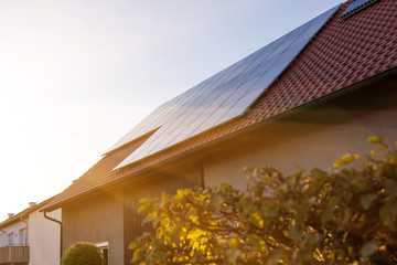 Solar panels on the tiled roof of the building in the sun set.