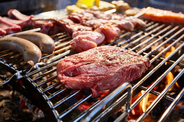 The meat is pickled on a lattice grill, ribs spread, a stake, Sausages, edges, chicken, naked flame, black pepper, a smoke, firewood, light reflections, close up