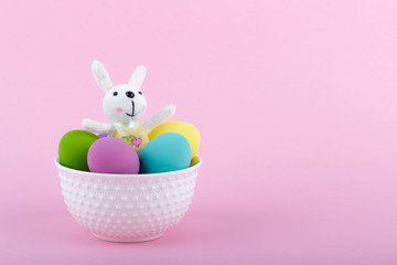 New spring happy easter concept. Colorful easter eggs in a white ceramic bowl with a soft toy...