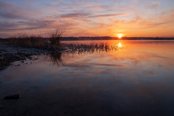 Gorgeous sunrise over the lake with reflection of the sun on the lake and spring