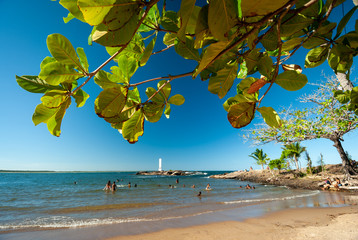 Tourists on the beach of the shells on a sunny afternoon, where you can see the lighthouse in the...