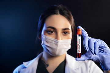 Woman doctor holding a blood test which is signed as covid-19 positive.