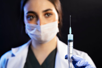 Doctor or nurse woman holds injection syringe and vaccine.