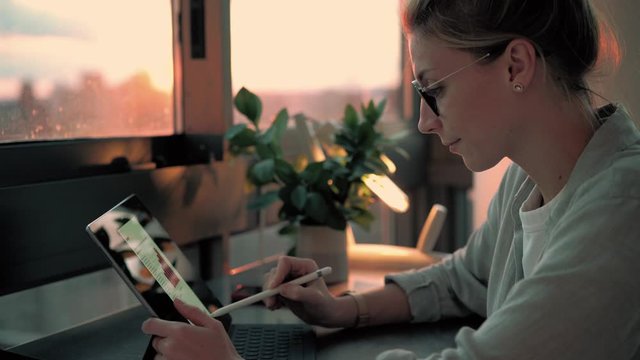 Smart casual millennial freelancer working remotely with financial diagrams using electronic pen and touch pad, skilled female student doing e learning for create graph charts with stylus