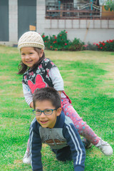 kids laughing brothers in green garden, sister rides her brother