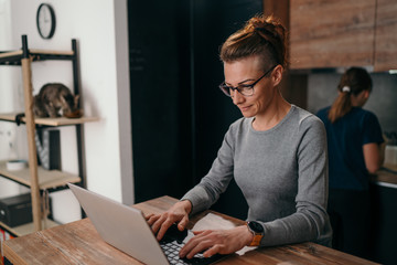 Single mother working on laptop online while her daughter and cat have lunch