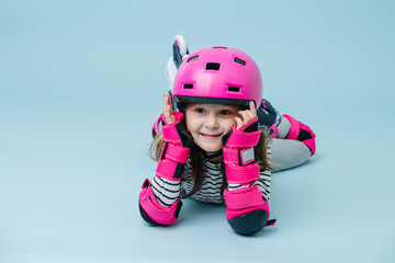 Wondeing little girl in roller skates in a gear lying on the floor
