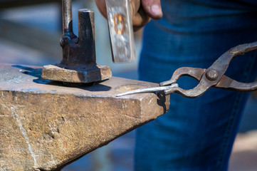 blacksmith performs the forging of hot glowing metal on the anvil