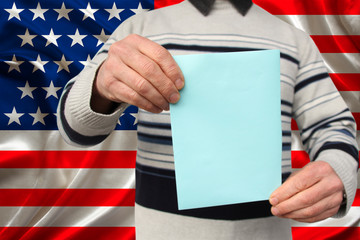 male voter lower the ballot in a transparent ballot box against the background of the national flag of the USA country, concept of state elections, referendum