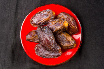 Big luxury dried date fruit in bowls on the dark surface, kurma ramadan kareem concept, close up.