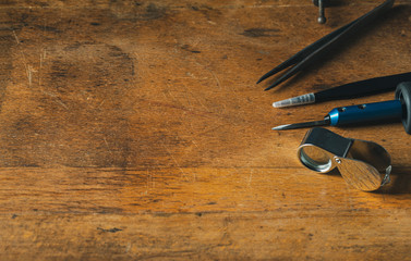 Jewelry craftsmanship. Handmade. Jeweler at work. The jeweller engraver tools on wooden vintage desk. Tweezers, Magnifier, Chisel Hand Engraving Top view