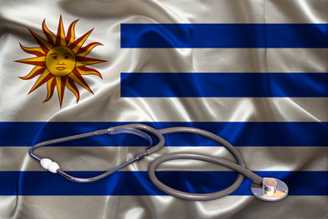 Fototapeta premium doctor’s tool, medical stethoscope, lies on the silk national flag of the state of Uruguay, concept of tourism, insurance, health, pediatrics