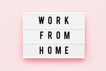 WORK FROM HOME written in light box on pink background. Healthcare and medical concept. Top view. Quarantine concept.