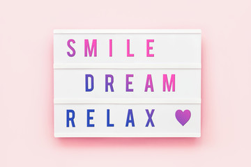 SMILE DREAM RELAX written in light box on pink background. Healthcare concept. Motivation quote. Top view.