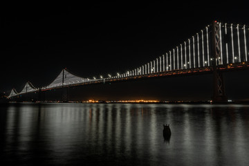 Fototapeta na wymiar Natural San Francisco Bay Bridge with Oakland in background and water reflection night photo. Bay Area, California. 