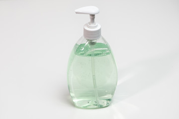 Hand sanitizer bottle on a white table, important in virus prevention.