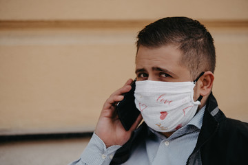 White bearded adult man using smartphone while wearing surgical mask.