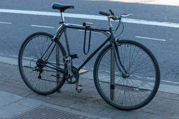 a close up view of a black bycycle locked onto a bike pole outside a shupermarket